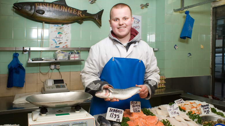 Smiling fishmonger holding a whole fish