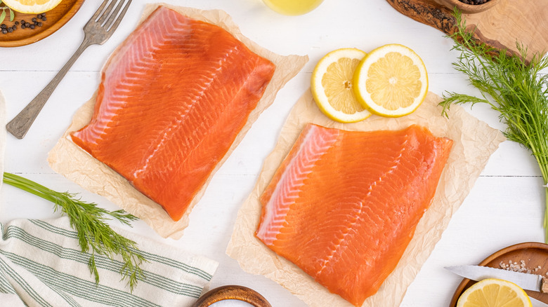 Fresh salmon fillets on table with lemons and herbs
