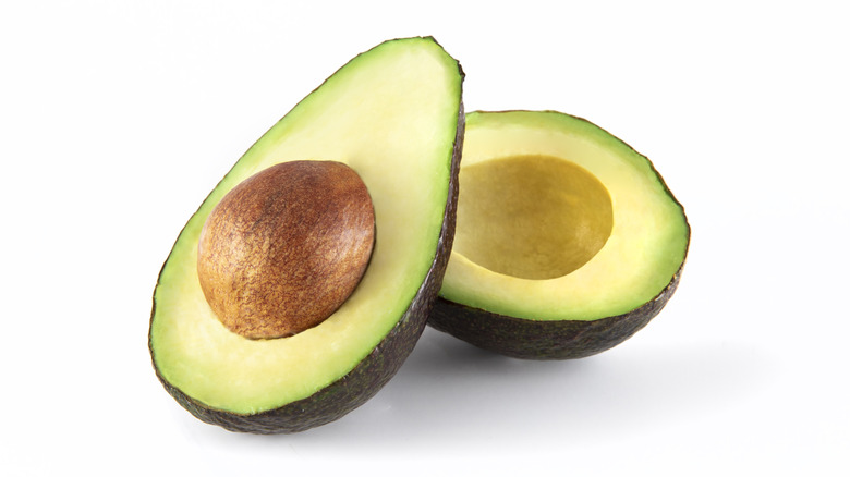 Two avocado halves, one with the pit inside of it