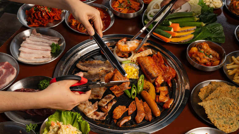 People grilling Korean BBQ meat and vegetables on a smokeless grill