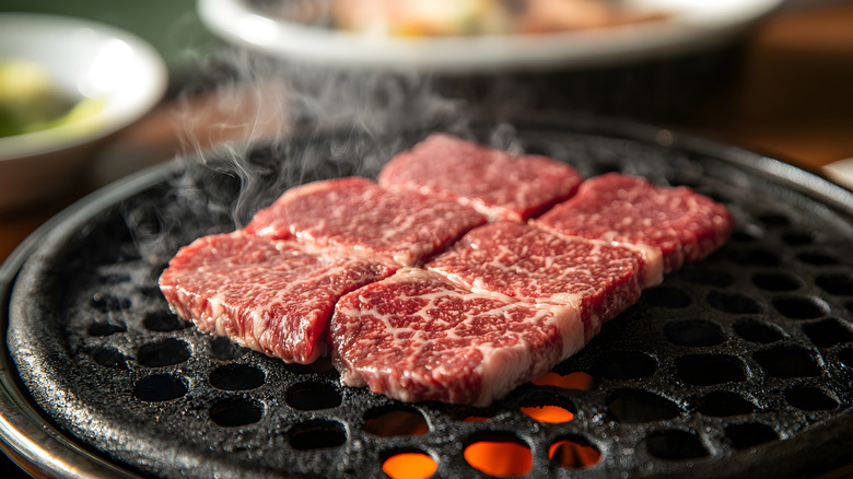 Sizzling marbled Wagyu beef short rib cooking on a hot tabletop grill