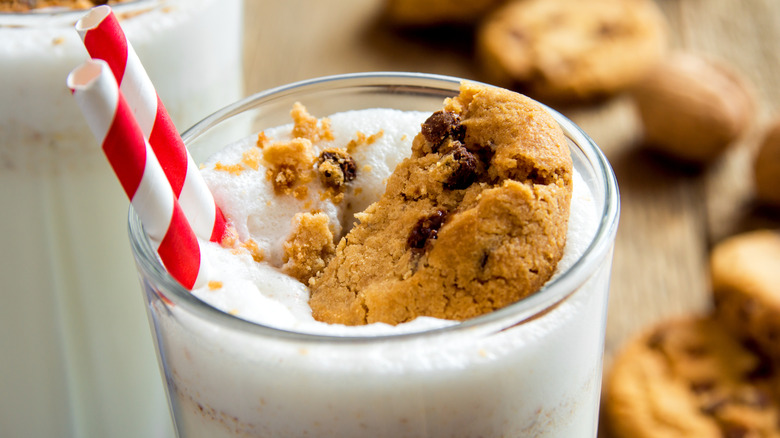 milkshake with chocolate chip cookies on top and two red and white straws