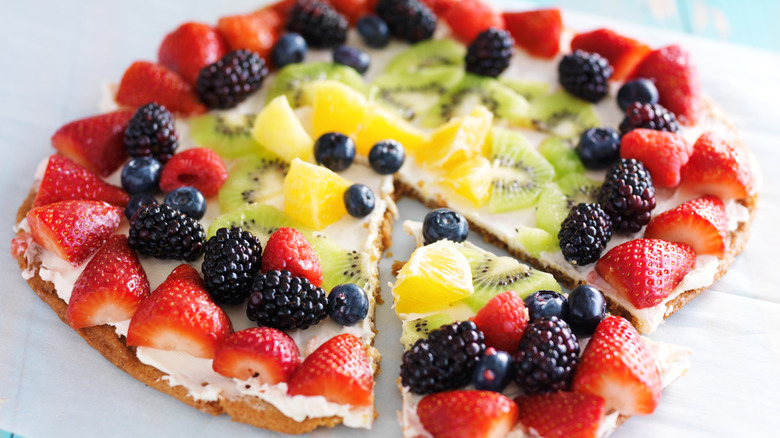 close up of a cookie pizza with white frosting and assorted fruit