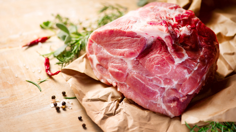 Raw meat surrounded by spices on a wooden table
