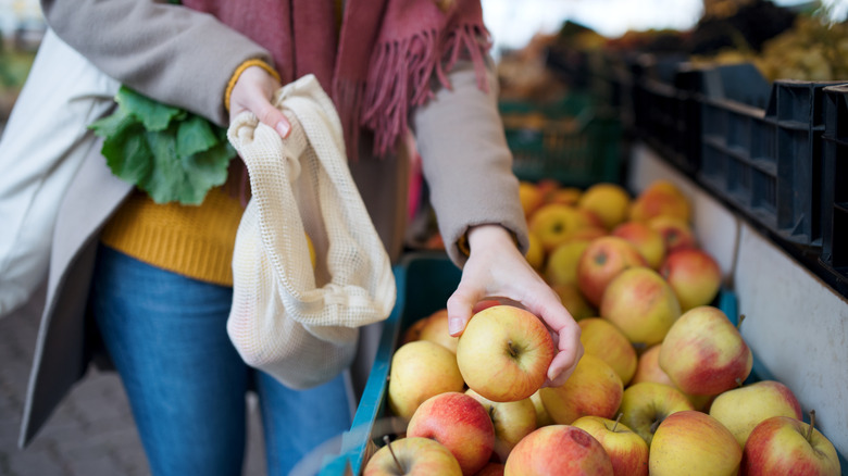 A woman putting apples into a reusable bag