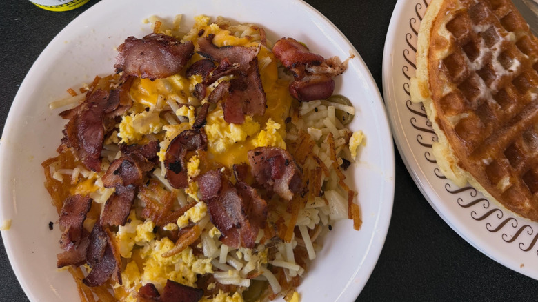 A plate of Waffle House eggs covered in ham, hash browns, and cheese.