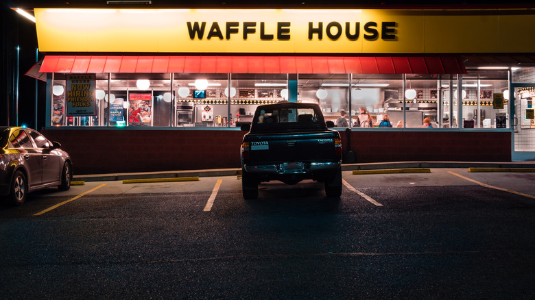 A Waffle House parking lot at night with several empty parking spaces.