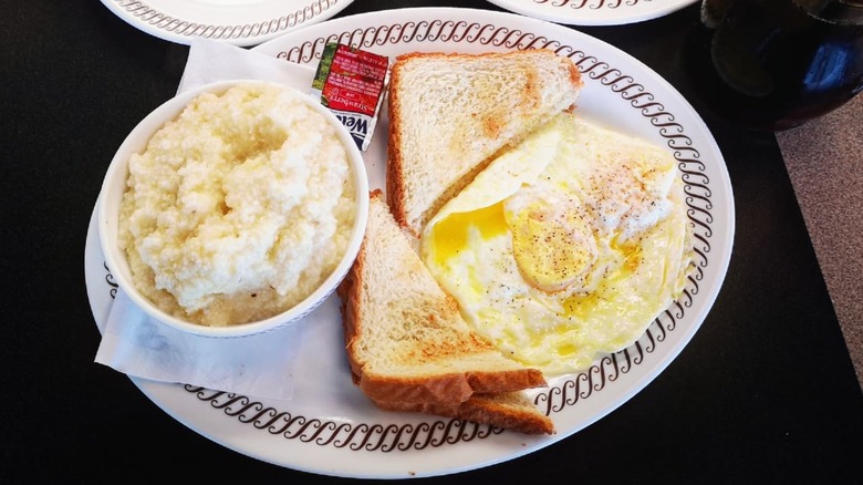 A bowl of Waffle House grits on a plate with eggs over easy and toast.