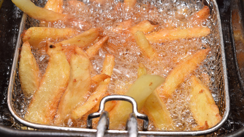 Home made fries in a hot deep fryer with boiling oil