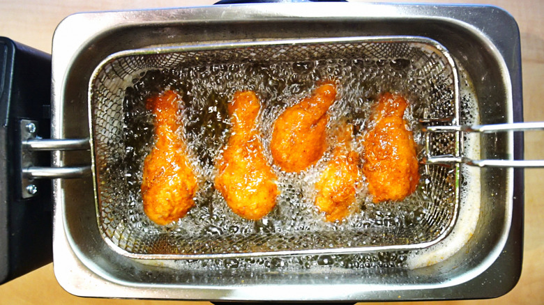 Chicken frying in the basket of a countertop deep fryer