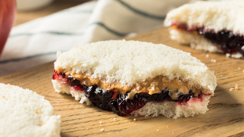crustless peanut butter and jelly sandwich cut in half on wooden board