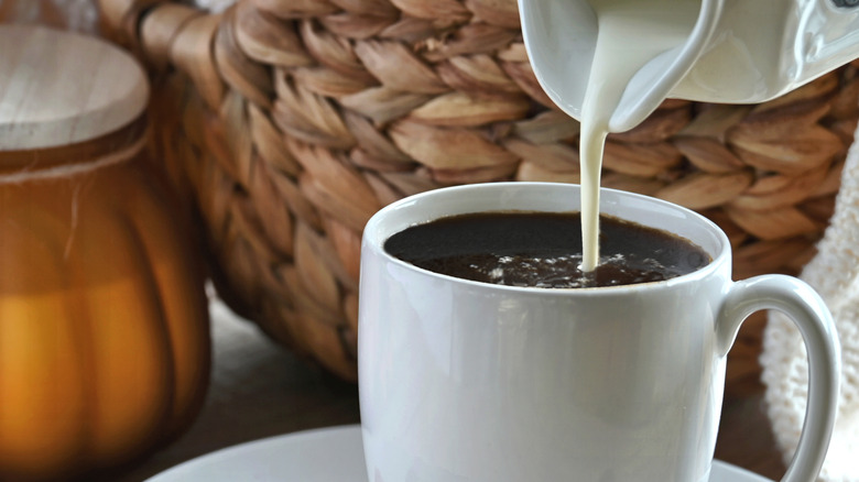 Cream being poured into a cup of coffee