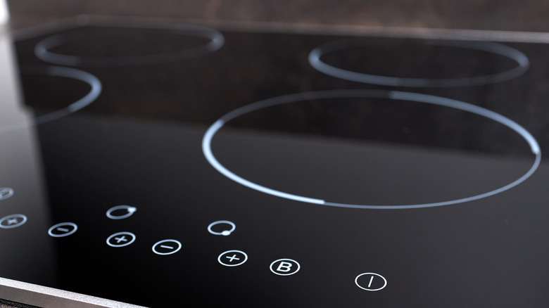 Modern induction electric hob cooker with control panel buttons. Electric hob detail closeup.