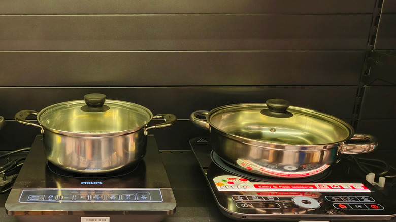 Two pans lined up on induction cooktops in a store