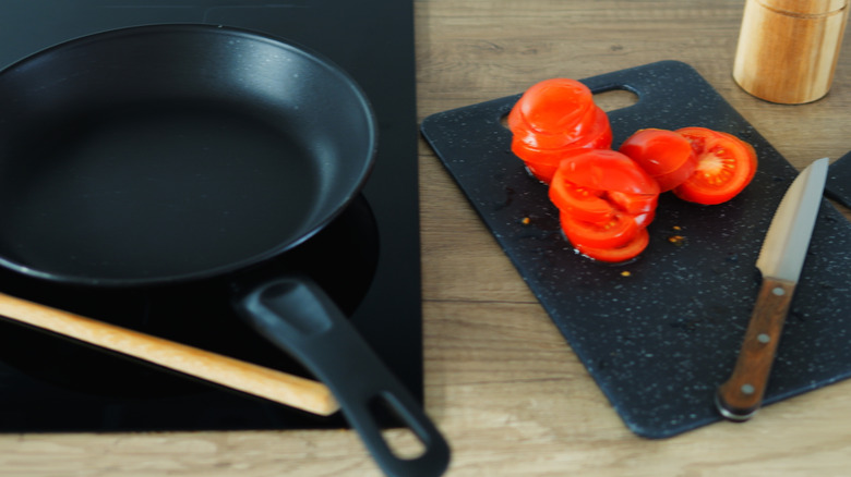 Sliced tomatoes on a cutting board near stove in kitchen