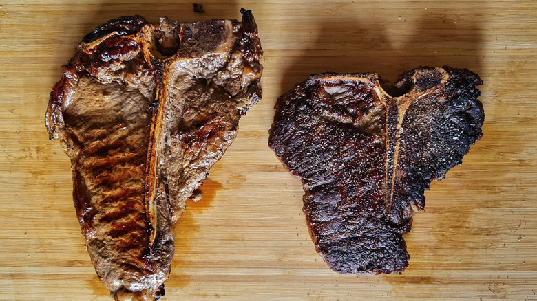 Top down view of well-done and medium cooked steaks on a wooden cutting board