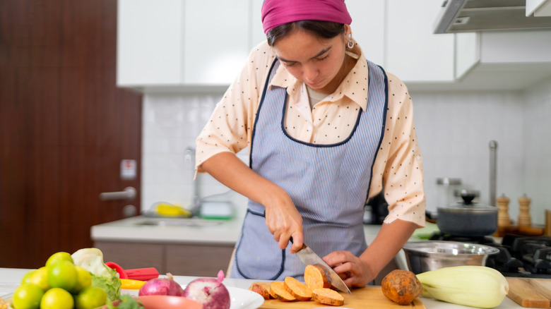 Woman concentrating on cutting food in a kitchen