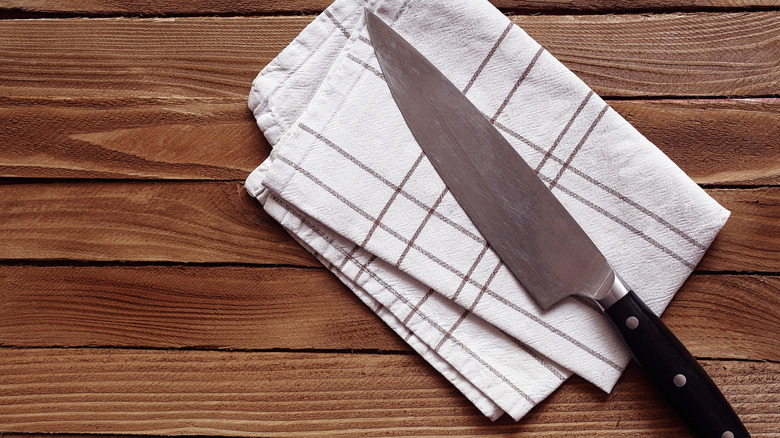 Chefs knife on a towel on a wooden surface