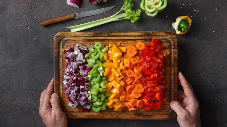 Assorted sliced vegetables on a cutting board next to a knife