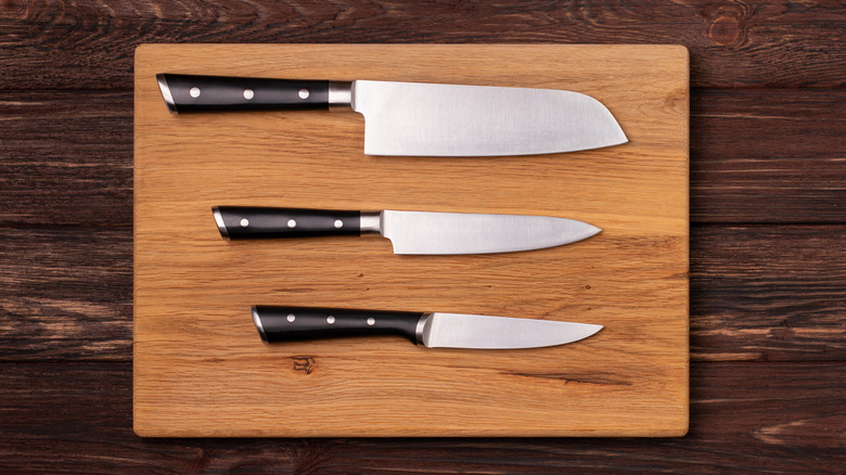 Three kitchen knives on a wooden cutting board