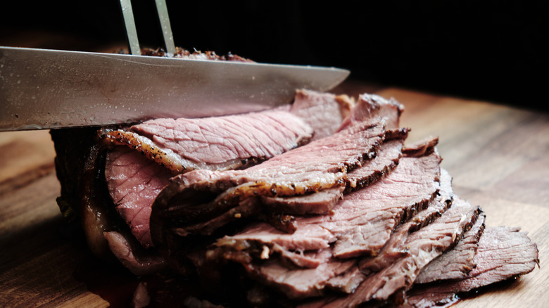 Roast beef being sliced on a cutting board