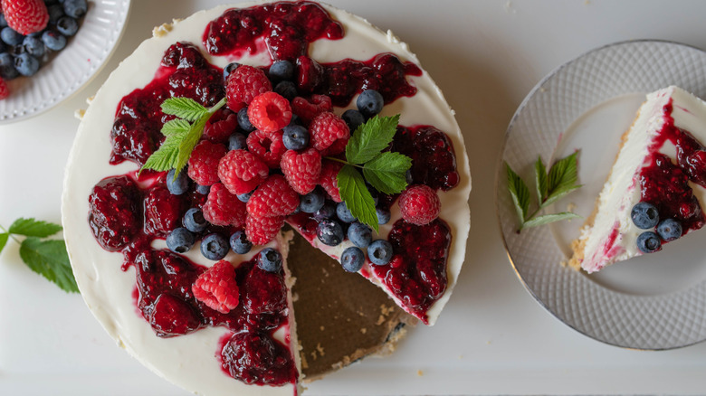 No-bake cheesecake with fresh berries and berry compote on white counter