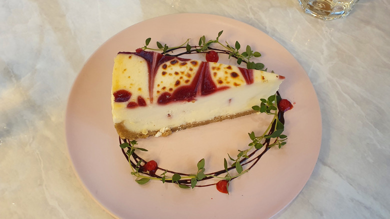 a slice of cranberry chocolate cream cheese cake with garnish on a white plate