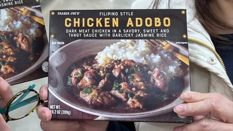 A woman holding Filipino-style chicken adobo inside a Trader Joe's