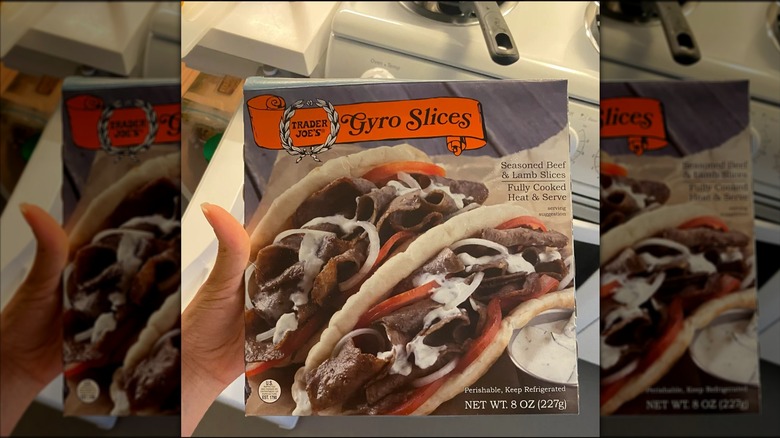 A hand holding a box of Trader Joe's gyro slices