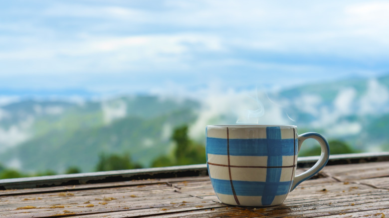 Steaming cup of coffee with mountains in background