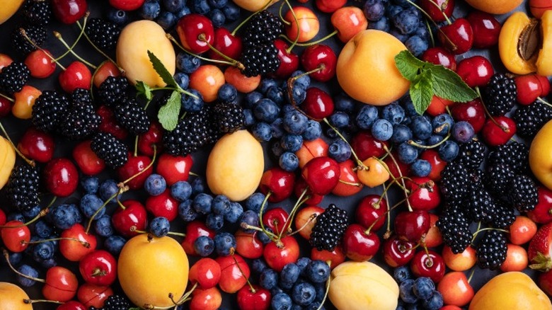 a flat lay of fruits including cherries, blackberries, blueberries, and peaches