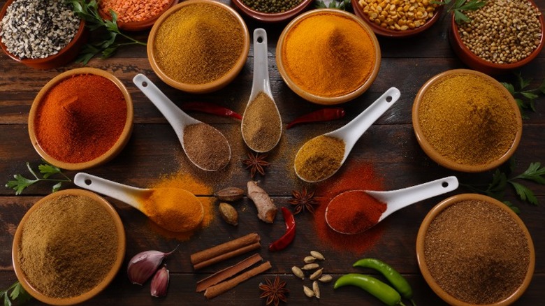 small bowls and spoons filled with red, orange, and brown spices