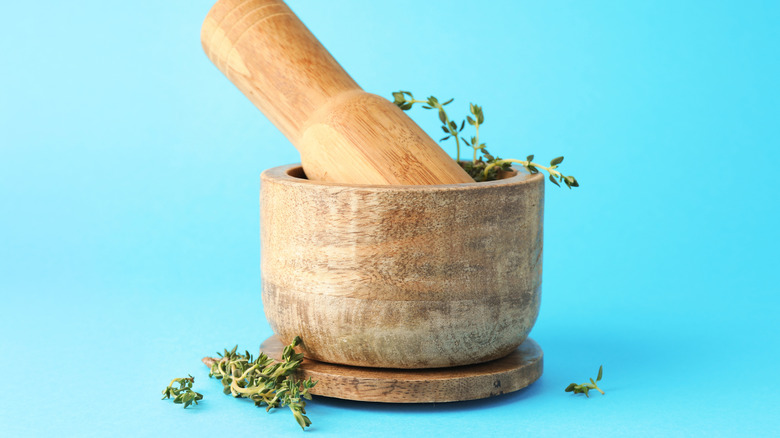 Wooden mortar with sprigs of thyme and pestle