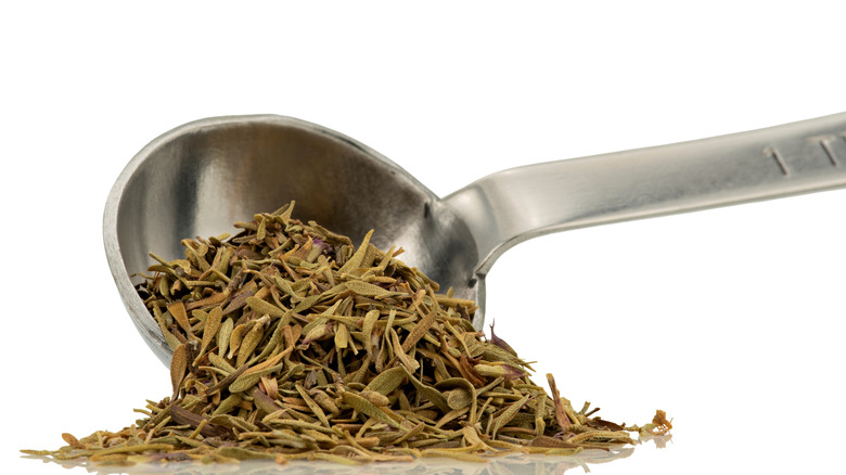 Measuring spoon of thyme isolated on a white background