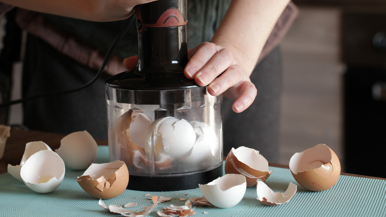 Person grinding eggshells in a food processor