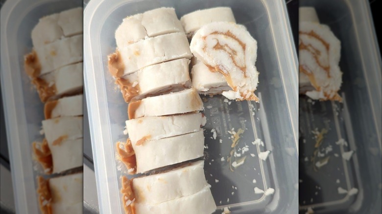 a plastic container filled with circular potato candies with a peanut butter swirl