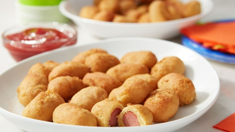 Great Value mini corn dogs in a white bowl next to a cup of ketchup