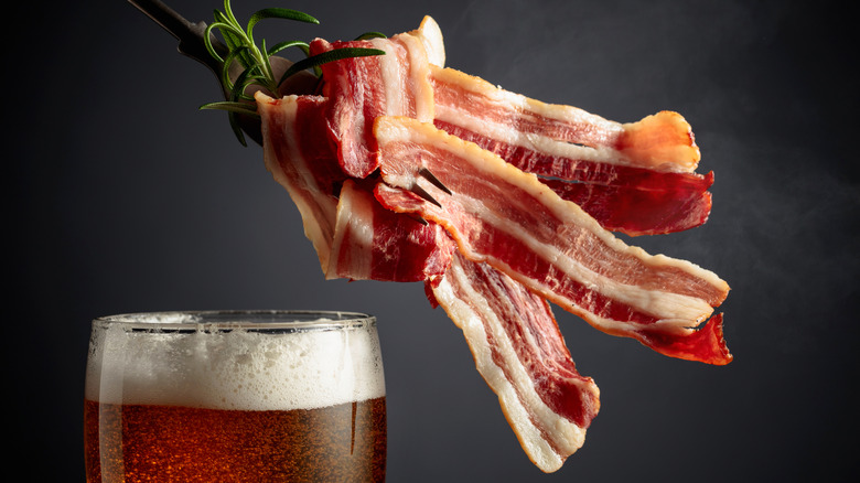 A foamy glass of beer with raw bacon