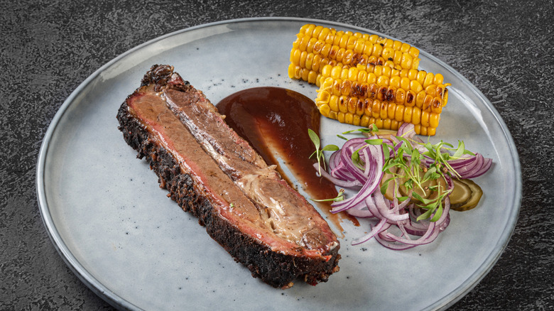 Smoked meat and corn on a white plate