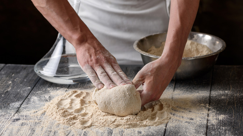 A man kneading pizza dough on a wooden table