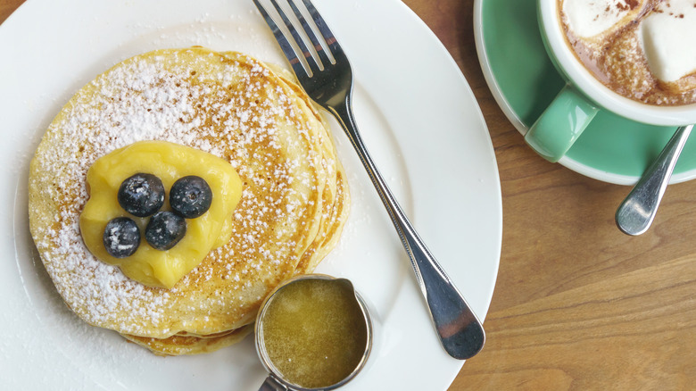 Pancakes topped with lemon curd and blueberries on a white plate