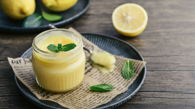 Homemade lemon curd in a jar and fresh mint leaves