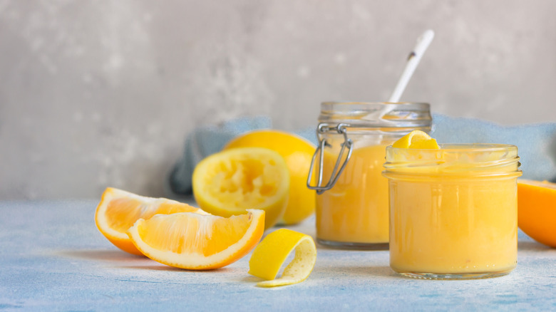 Homemade lemon curd in jars surrounded by fresh lemons