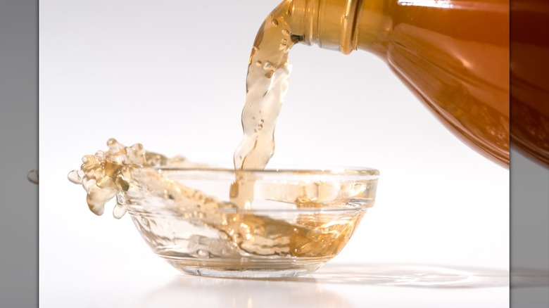 Apple Cider Vinegar splashes as it is poured into a small, glass ingredient bowl