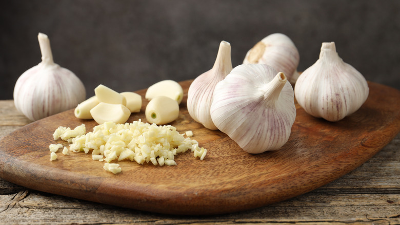 Chopped garlic and bulbs on wooden table, closeup.