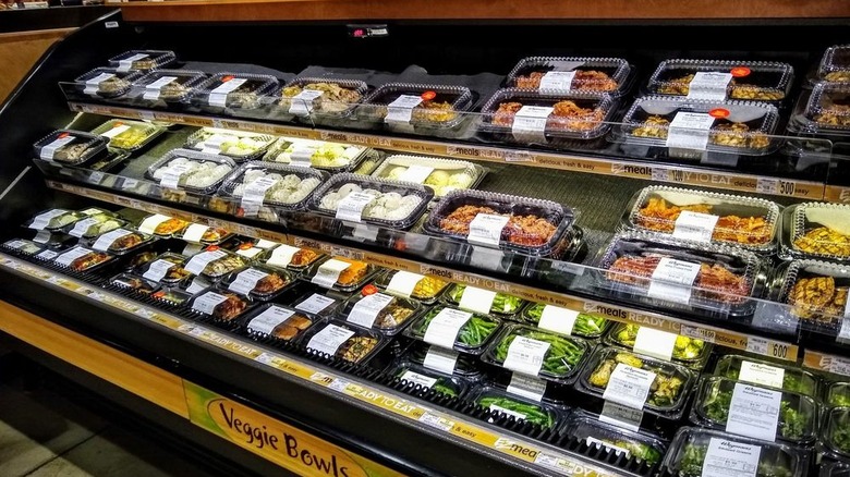 A display case of Wegmans EZ meals including veggie bowls and pre-cooked meats in plastic containers