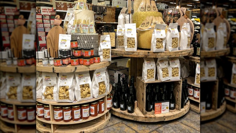 Wegmans premium products on decorative wooden displays including Amore pasta, Italian Classics Parmigiano Reggiano and more