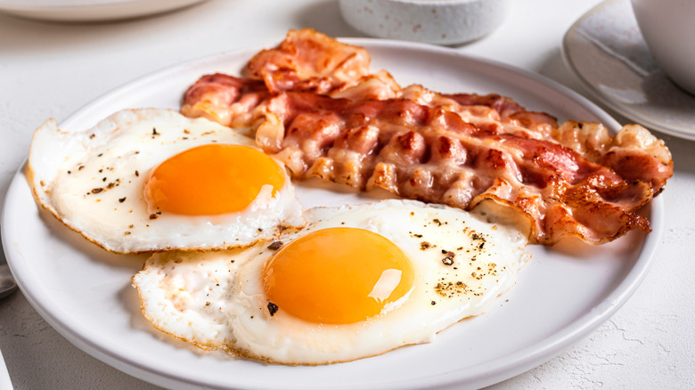 Two fried eggs and bacon on a white plate