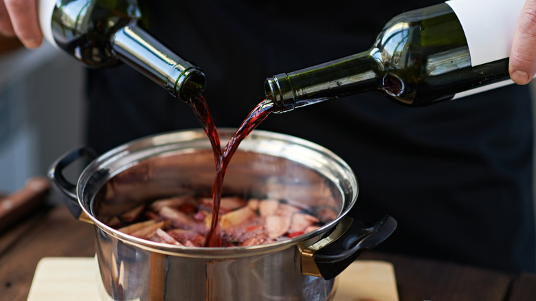 Wine being poured into a pot of soup