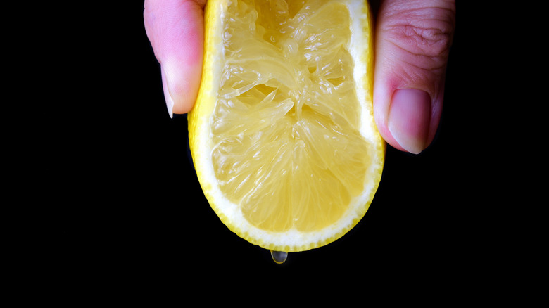 Fingers squeezing a fresh lemon